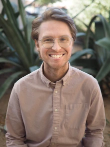 An individual wearing glasses smiles for a photo.