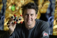 A person holding a detailed model of a molecule represented by spheres connected by curved bars