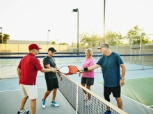 Four older people playing pickleball