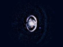 The star, WISPIT 2, appears a bright spot in the center, surrounded by a white, bright ring of dust. Two small dots indicate the growing protoplanets in the system. 