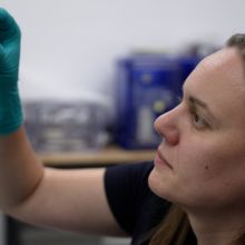 Jessica Barnes looking at a vial containing Bennu asteroid sample