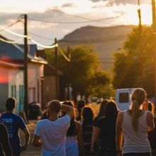 a group of people walking down the street toward a setting sun