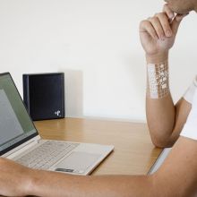 a person sitting at a computer with a device on their arm