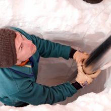Matthew Osman steadies an ice core drilling barrel into the Greenland Ice Sheet snow surface