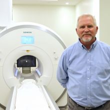Ted Trouard standing next to an advanced MRI machine