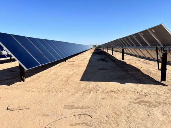 Solar panels cast a shadow on brown earth
