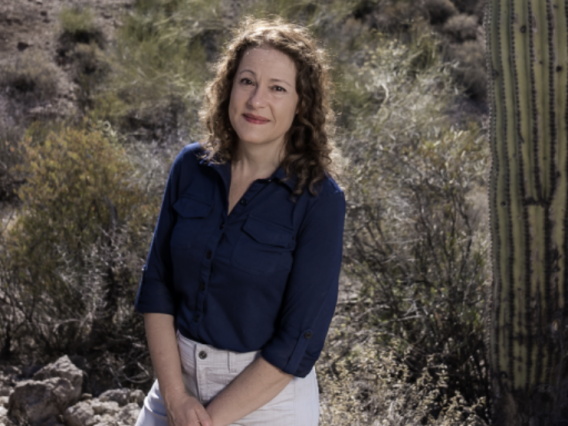 Carmala Garzione smiling, standing near saguaro cacti in the desert