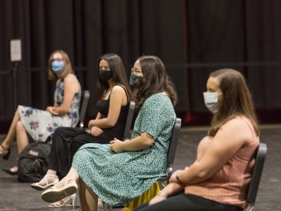 four female students wearing masks, seated spaced apart
