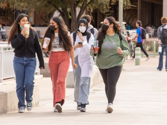 four female students wearing masks and walking on campus