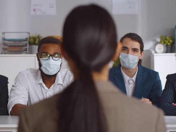woman being interviewed by four people wearing masks