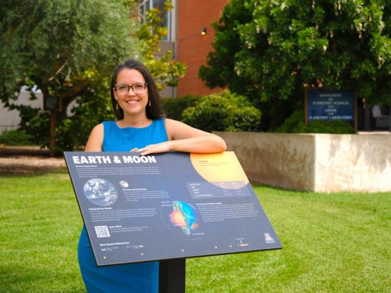 Doctoral student Zarah Brown with the plaque for &quot;Earth and moon,&quot; which is part of solar system scale model installed on the UArizona campus