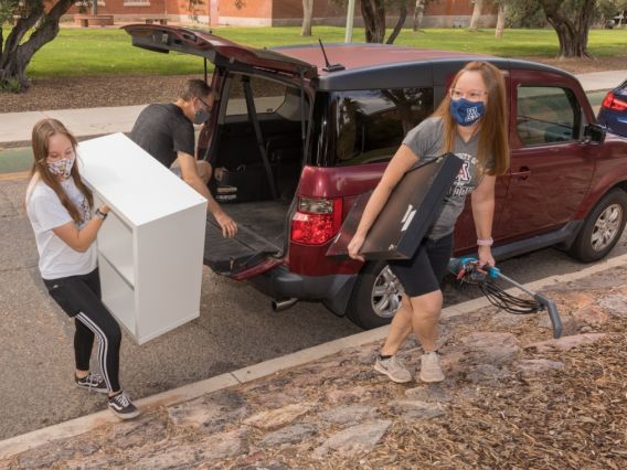 masked people moving furniture into a dorm