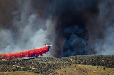 large airplane dropping fire retardant on a wildfire