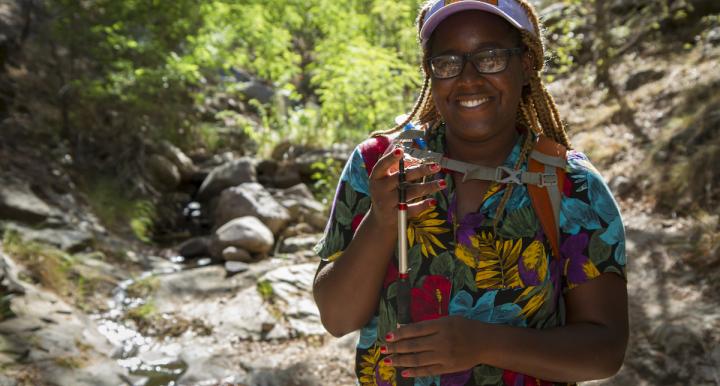 Earyn McGee holding a lizard in a dry stream bed in the Chiricahua Mountains