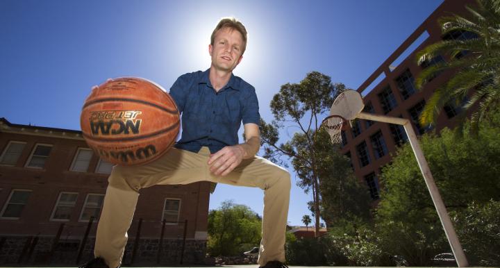 UA physicist Sam Gralla dribbles a ball on the basketball court.
